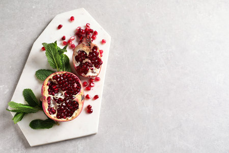 Board with ripe pomegranates and seeds on gray background, top view. Space for textの写真素材