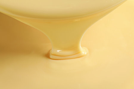 Tasty pouring condensed milk as background, closeup. Dairy productの写真素材