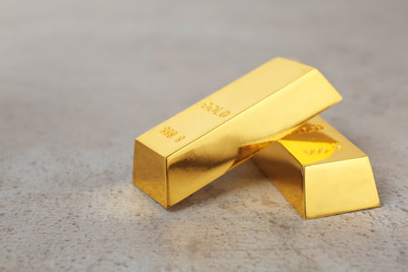 Two shiny gold bars on table. Space for text