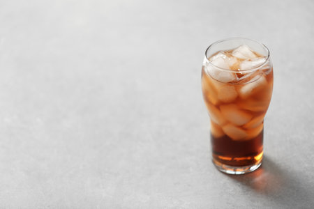 Glass of cola with ice on light background, space for textの写真素材