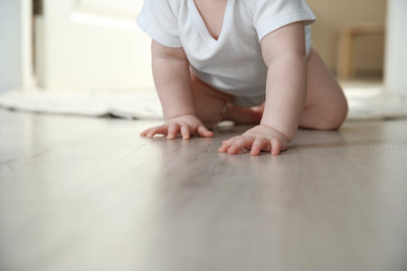Cute little baby crawling on floor indoors, closeup with space for textの写真素材