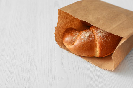 Paper bag with pastry on light wooden background. Space for textの写真素材