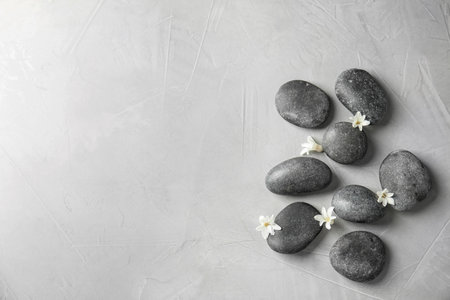 Zen stones and exotic flowers on gray background, top view with space for textの写真素材