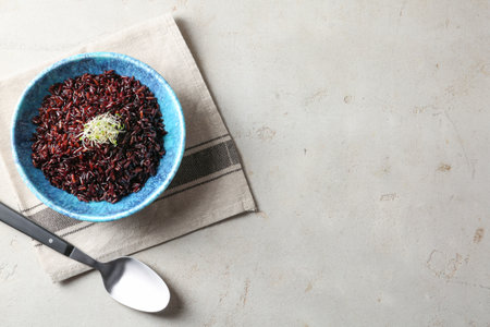 Bowl of boiled brown rice and spoon on table, flat lay. Space for textの写真素材