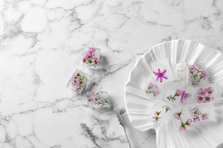Flat lay composition with floral ice cubes on marble background. Space for textの写真素材