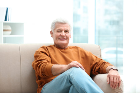 Portrait of handsome mature man on sofa indoorsの写真素材