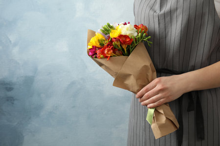 Woman holding bouquet with beautiful freesia flowers on color background, closeup. Space for textの写真素材