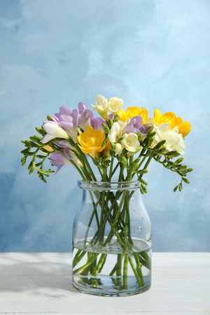 Bouquet of fresh freesia flowers in vase on table. Space for textの写真素材