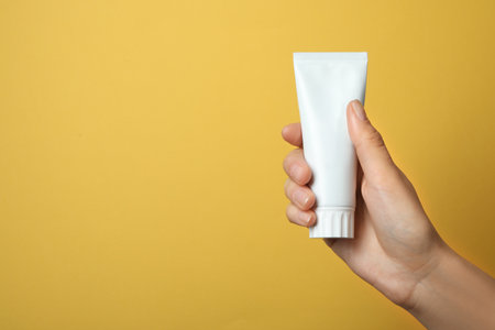 Woman holding blank toothpaste tube on color background. Space for textの写真素材