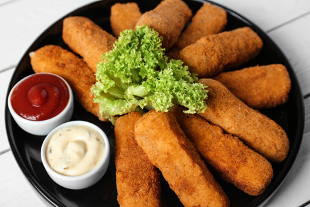 Plate of cheese sticks and sauces on table, closeup