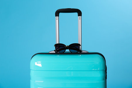 Stylish suitcase with sunglasses on color backgroundの写真素材