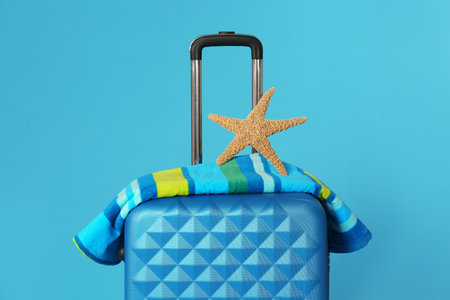 Stylish suitcase with towel and sea star on color backgroundの写真素材