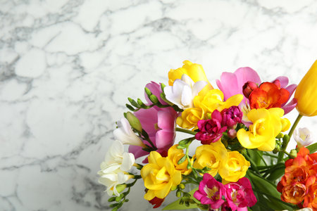 Beautiful spring freesia flowers on marble background, top view. Space for textの写真素材