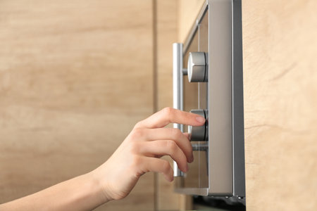 Young woman adjusting modern microwave oven in kitchen, closeupの写真素材