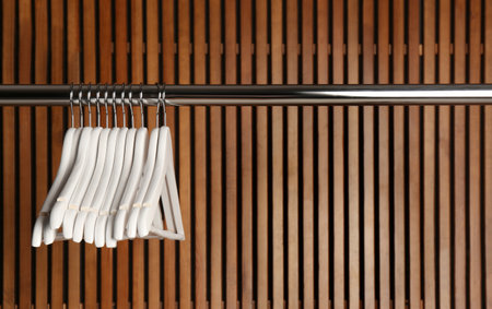 Empty hangers on rail against wooden backgroundの写真素材
