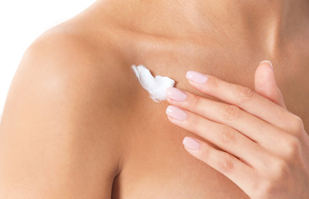 Young woman applying cream on light background, closeup. beauty and body careの写真素材