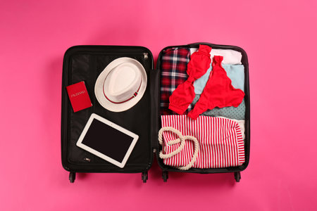 Open suitcase with traveler's belongings on color background, top viewの写真素材
