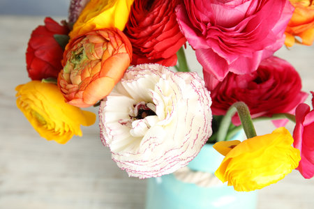 Bouquet of beautiful bright ranunculus flowers in vase on light table, closeupの写真素材