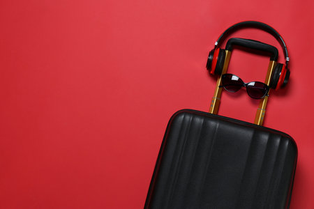 Stylish suitcase with sunglasses and headphones on color background, top view. Space for textの写真素材