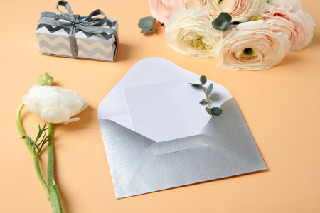 Beautiful ranunculus flowers, gift box and card in envelope on color background. Space for textの写真素材
