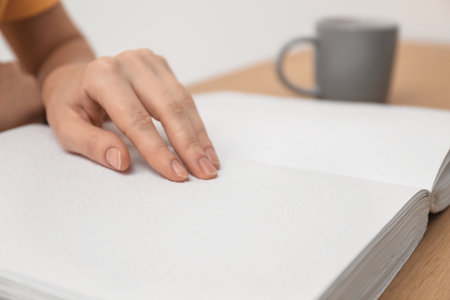 Blind woman reading book written in Braille at table, closeupの写真素材