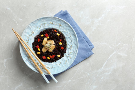 Plate with cooked brown rice and chopsticks on table, top view. Space for textの写真素材