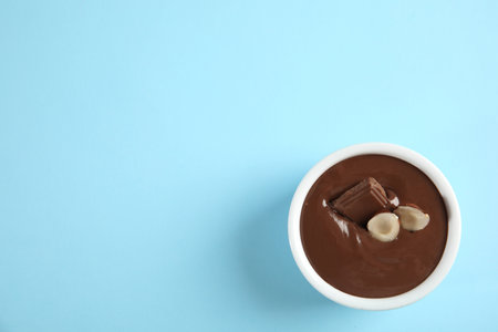Bowl with sweet chocolate cream and hazelnuts on color background, top view. Space for textの写真素材