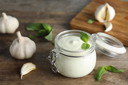 Composition with jar of garlic sauce on wooden tableの写真素材
