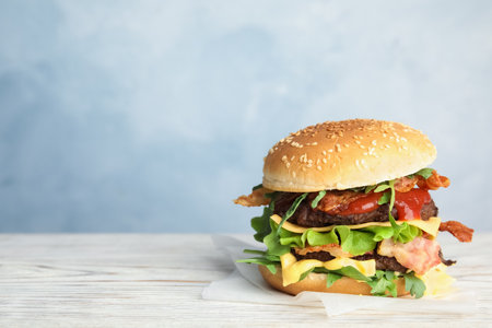 Tasty burger with bacon on table against color background. Space for textの写真素材