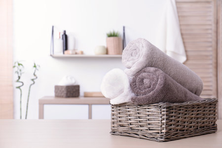 Basket with rolled fresh towels on table in bathroom. Space for textの写真素材