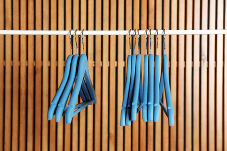 Empty hangers on rail against wooden backgroundの写真素材