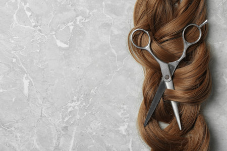 Flat lay composition with brown hair, scissors and space for text on gray background. hairdresser serviceの写真素材