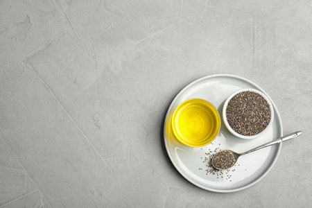 Plate with chia oil, seeds and spoon on gray background, top view. Space for textの写真素材