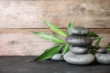 Stacked zen stones and bamboo leaves on table against wooden background. Space for textの写真素材