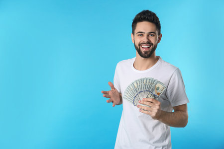 Portrait of happy young man with money on color background. Space for textの写真素材