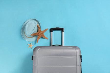 Stylish suitcase, sea stars and hat on color background, top viewの写真素材