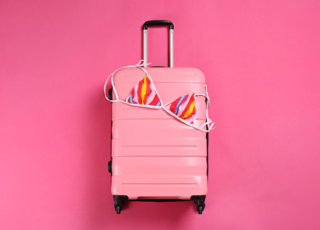 Stylish suitcase with bikini top on color background, top viewの写真素材