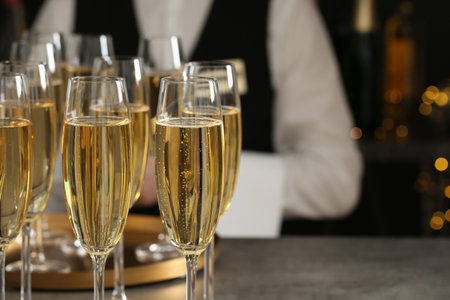 Glasses of champagne and waiter in restaurant, closeup. Space for textの写真素材