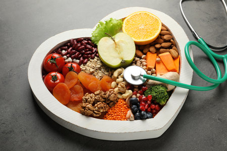 Heart shaped tray with healthy products and stethoscope on gray backgroundの写真素材