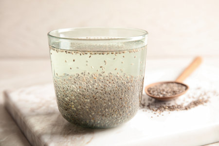 Glass of water with chia seeds and spoon on boardの写真素材