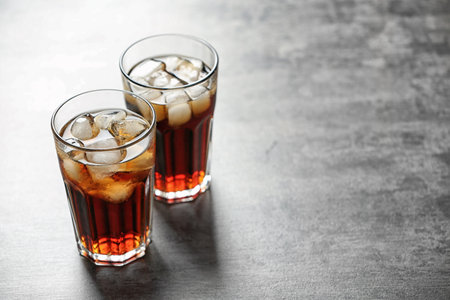 Glasses of cola with ice on gray background, space for textの写真素材