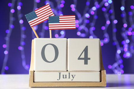 Wooden calendar with USA flags on table against blurred lights, closeup. Happy Independence Dayの写真素材