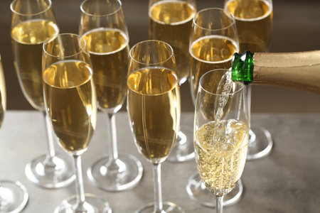 Pouring champagne into glasses on table, closeup viewの写真素材