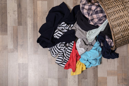 Dirty clothes scattered from laundry basket on floor, top view. Space for textの写真素材