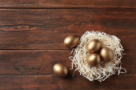 Nest with golden eggs on wooden background, top view. Space for textの写真素材