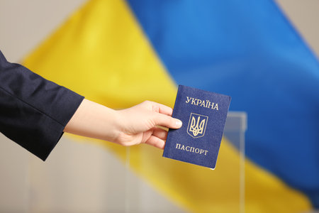 Woman holding Ukrainian internal passport against national flag at polling station, closeupの写真素材