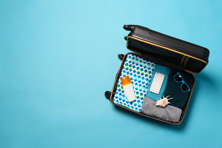 Open suitcase with traveler's belongings on color background, top view. Space for textの写真素材