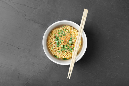 Cup of instant noodles with chopsticks on gray background, top viewの写真素材