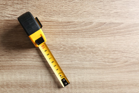 Metal measuring tape on wooden background, top view. Space for textの写真素材