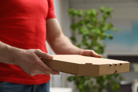 Courier with pizza box on blurred background, closeupの写真素材